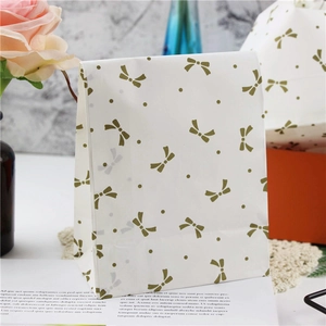 Detail of white paper gift bag with elegant gold bow pattern and polka dot print