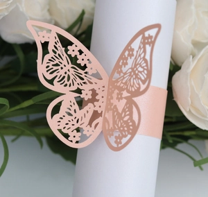 Detail showing a pink laser-cut paper butterfly napkin ring on a white scroll