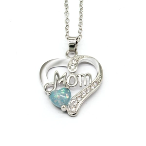 Close-up of heart-shaped silver necklace with blue opal and Mom lettering detail