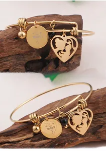 Detail of gold bangle with Happy Mother's Day charm and mother-child heart pendant