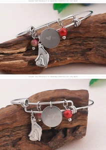 Detail of silver bangle with I Love You charm and red beads on rustic wood background