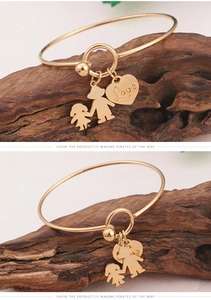 Détail du bracelet en titane doré avec breloque cœur et pendentifs garçon et fille