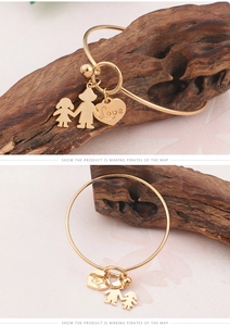 Vue détaillée du bracelet doré avec charms Love et figurines sur un support en bois
