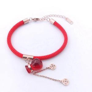 Detail of red woven rope bracelet with rose gold coins and gourd charm on white background