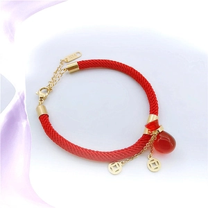 Detail of red braided bracelet with gold coin charms and a red teardrop pendant
