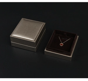 Detail of champagne leatherette jewelry boxes with heart necklace in brown velvet lining