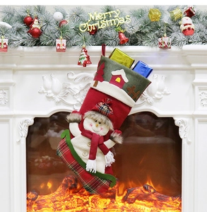 Christmas stocking with snowman and gift boxes hanging on a warm fireplace mantle