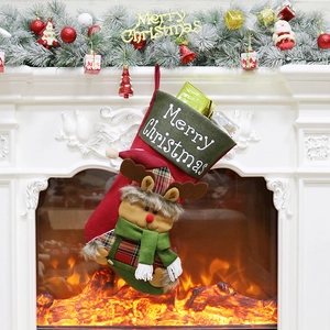 Festive red and green Christmas stocking with reindeer plush hanging on fireplace