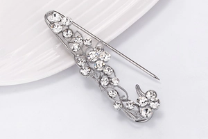 Close-up of silver vine brooch with sparkling rhinestones on a minimalist white plate