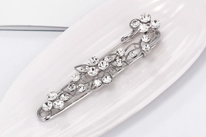 Detailed view of silver safety pin brooch featuring sparkling crystal flower and leaf patterns
