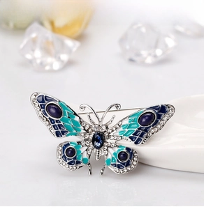 Detail of butterfly brooch with blue enamel wings and clear crystals on a ceramic tray