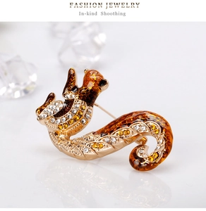Macro detail of golden squirrel brooch with amber enamel and sparkling rhinestones