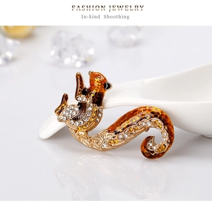 Detail of a squirrel brooch with amber enamel and rhinestones on a white spoon