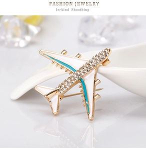 Detailed macro view of white enamel airplane brooch with blue wings and crystals