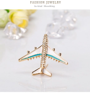 Close-up of golden aircraft brooch with enamel inlay and sparkling rhinestones