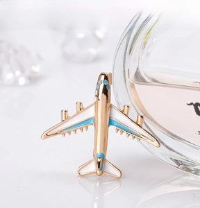 Detail of a gold-plated airplane brooch with blue enamel on a clear perfume bottle