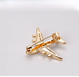 Detailed top view of gold metal airplane brooch featuring fine wing textures and safety pin