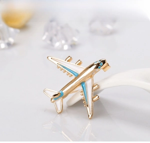 Detail of an airplane enamel brooch with gold-tone metal base and blue engine accents