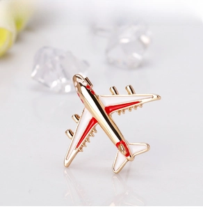 Detailed close-up of a white and gold airplane enamel brooch on marble surface