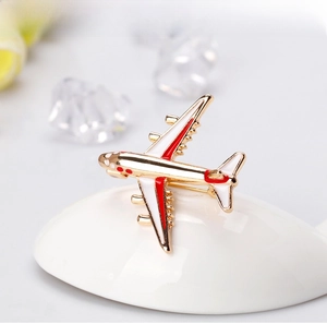Detail of a fashion airplane enamel brooch with gold base and red white accents