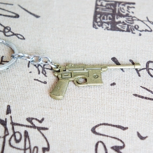 Detail of bronze metal pistol keychain with Crossfire engraving on textured fabric