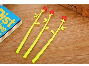 Close-up of three creative rose shaped pens with red petals and green stems on wood