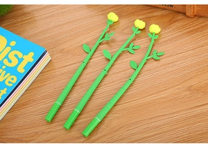 Detailed view of three creative yellow rose flower pens on a wooden desktop surface