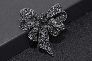 Detailed close-up of vintage black bow brooch with micro-paved black crystals and metal texture