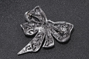 Detailed back view of vintage bronze bow brooch showing metal texture and pin fastener