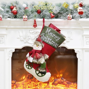 Classic red Christmas stocking with plush snowman on bicycle hanging on a cozy white fireplace