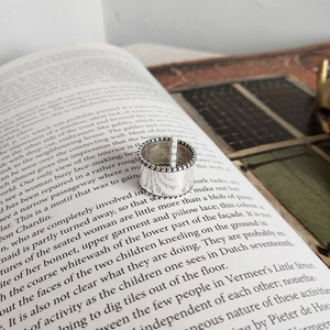 Detailed view of vintage S925 sterling silver wide band open ring on an open book