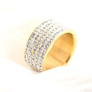 Luxurious gold titanium steel ring featuring five rows of shimmering crystals on white fabric