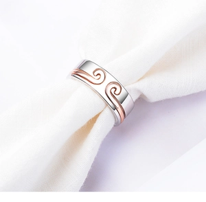 Detailed close-up of rose gold cloud patterns on a silver couple ring displayed on fabric