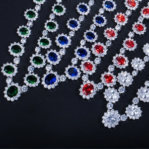 Détail macro de pierres ovales en émeraude, bleu, rouge et clair avec halo floral de diamants