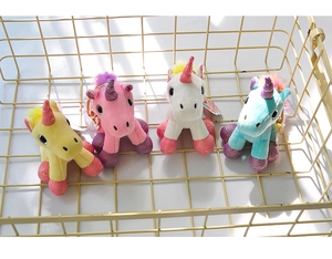 Close-up of four colorful plush unicorn keychains with sequins in a wire storage basket