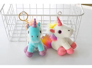 Close-up of blue and white plush unicorn keychains with rainbow manes and golden horns