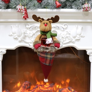 Christmas reindeer gift bag hanging on a cozy fireplace mantel with warm holiday decorations