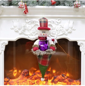 Detail of a snowman Christmas gift bag with plaid hat hanging on a festive fireplace