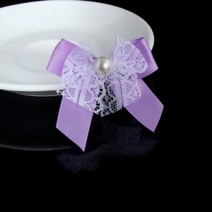 Detail of a purple satin bow with white lace layers and a pearl center accessory