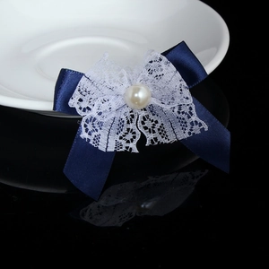 Detail of dark blue satin bow with white lace trim and a central white pearl ornament