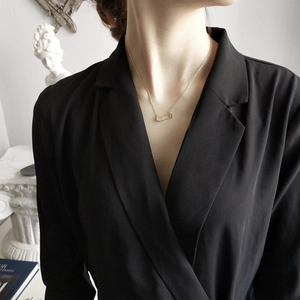 Detail of 18K gold-plated safety pin necklace with micro-pave crystals on model