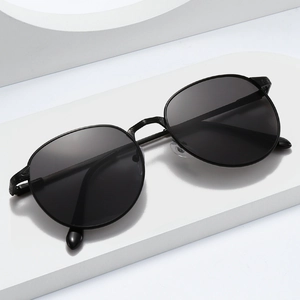 Classic black oval metal sunglasses with spring hinges on a minimalist white display stand