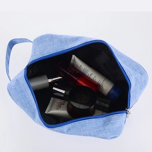 Top view of blue linen toiletry bag with handle, storage bottles, and zipper details