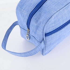 Close-up of sky blue toiletry bag showing durable oxford fabric texture and side handle strap