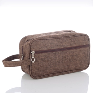 Macro shot of brown linen-textured men's toiletry bag with durable handle and zipper