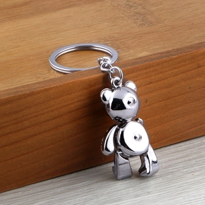 Polished silver metal teddy bear keychain with round ring on wooden background
