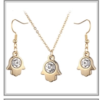 Detailed view of golden Hamsa Hand jewelry set with clear crystal pendant and earrings