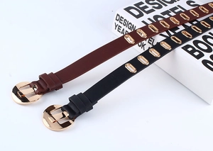 Detail view of black and brown PU leather belts with gold eyelets and round pin buckles