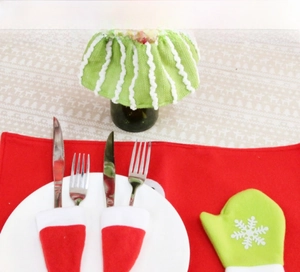 Set of festive Christmas cutlery holders and mini wine bottle covers on dining table
