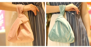 Fashionable velvet wrist bags in pink and green colors shown in a shopping mall setting